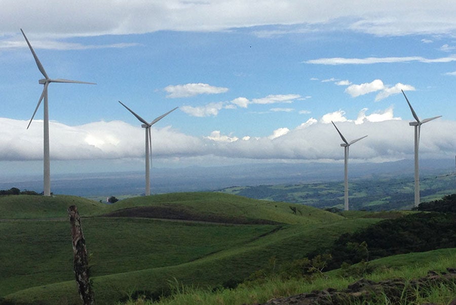 windmills in a green field with blue skies and clouds