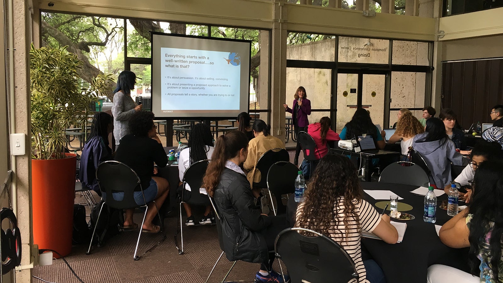 Students listening to a presentation with two lecturers