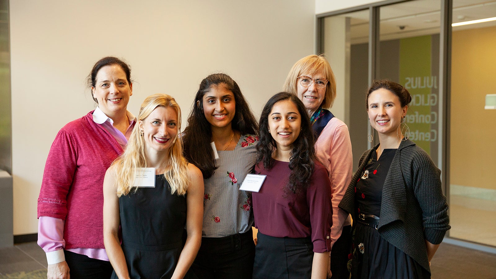 Four female students stand with three faculty members